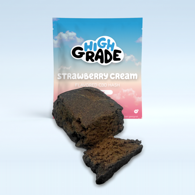 Strawberry Cream CBD-Hasch vor der HighGrade-Packung auf hellblaugrauem Studiogrund, mit aufgebrochenem Stück im Vordergrund